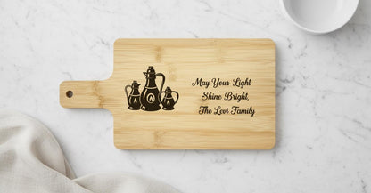 Personalized Hanukkah cutting board by The Present Spot, engraved with oil lamps and family name on acacia wood.